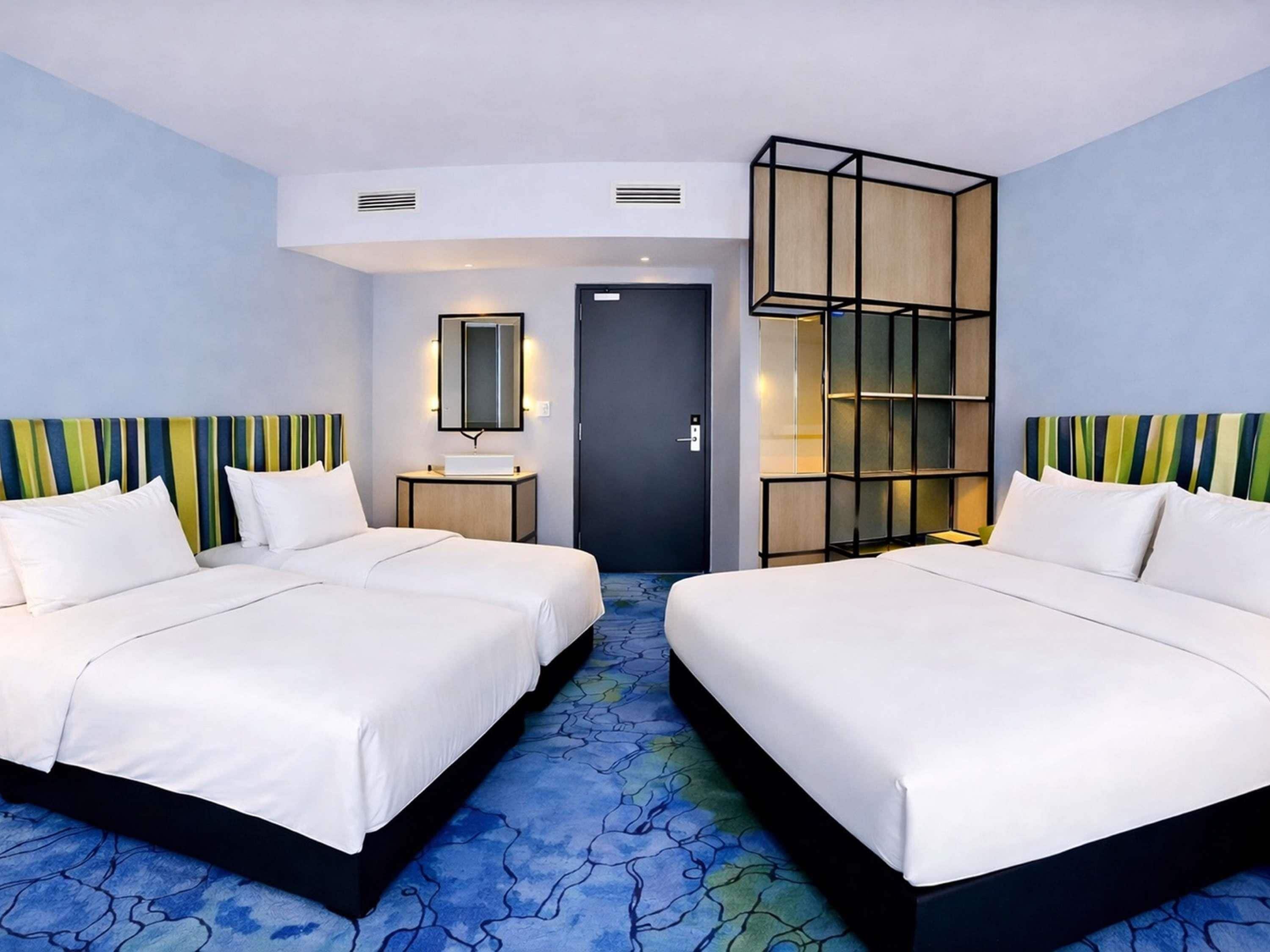Ein Hotelzimmer mit zwei Betten, einem Nachttisch, einem Spiegel und einem Kleiderschrank.