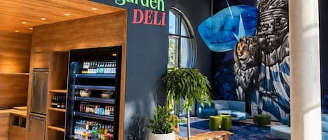Un interior moderno con una barra de deli, un refrigerador de bebidas y un mural de un león.