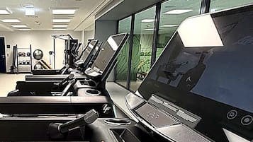 Een sportschool met loopbanden, trainingsapparatuur en grote ramen.