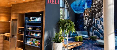 A modern interior with a deli named 'Isar Garden Deli,' a vending machine, and a mural of a figure with a lion.