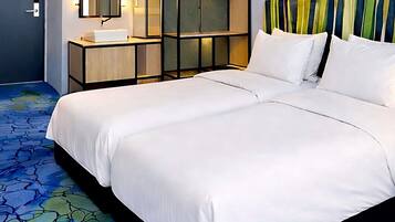 Habitación de hotel con una cama grande, una mesita de noche con lámpara, un espejo y un mueble de pared con estantes.