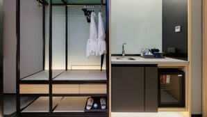 Un baño moderno con cabina de ducha de vidrio, lavamanos con artículos de aseo y zapatero empotrado.