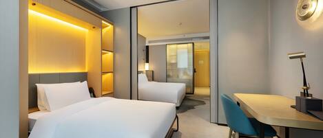 A hotel room with two beds, a desk, a chair, and a mirror.