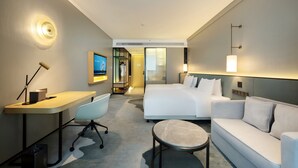 Una habitación de hotel con una cama, un escritorio, una silla, una mesa redonda y un sofá.