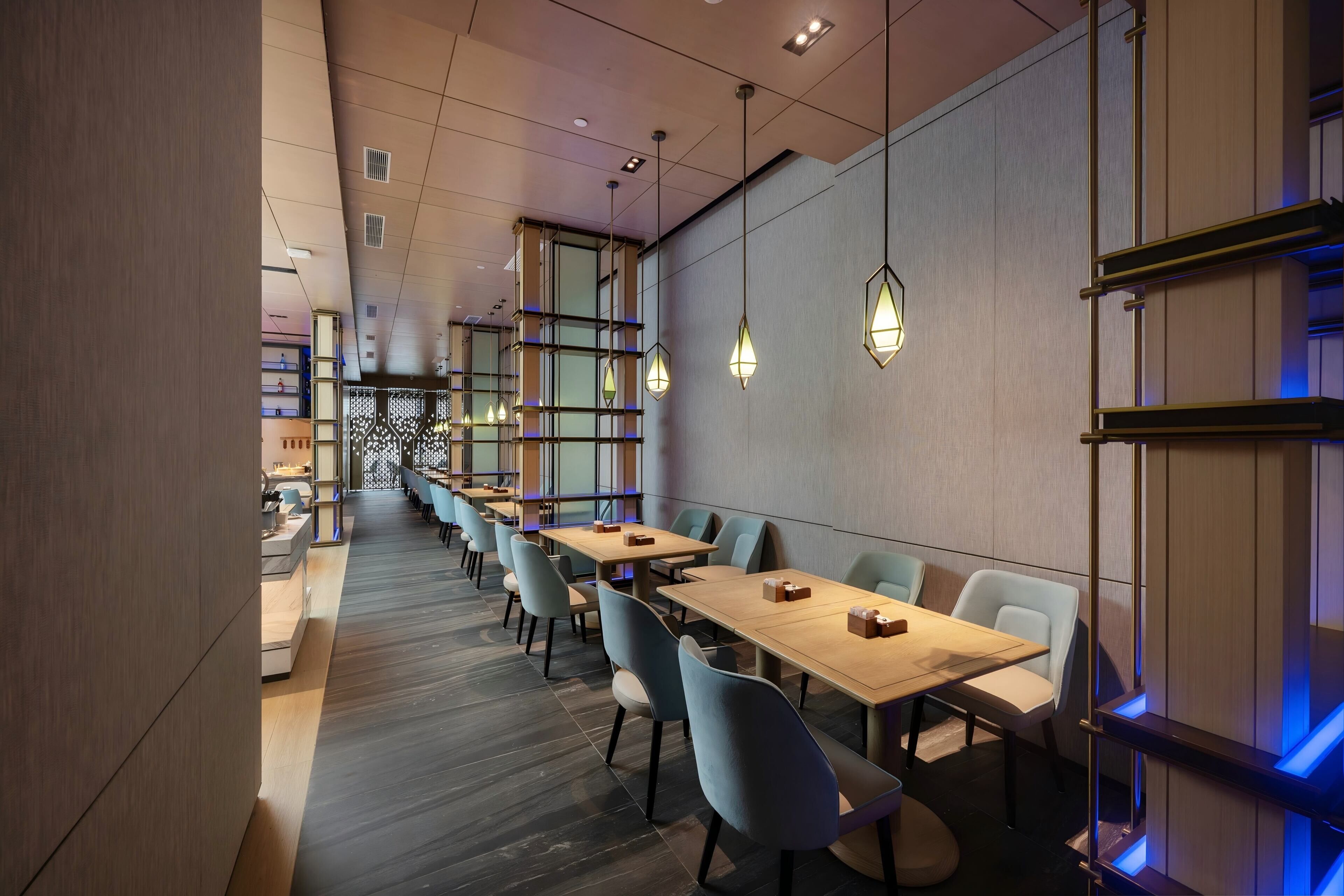 A modern dining area with long tables, chairs, and pendant lighting.