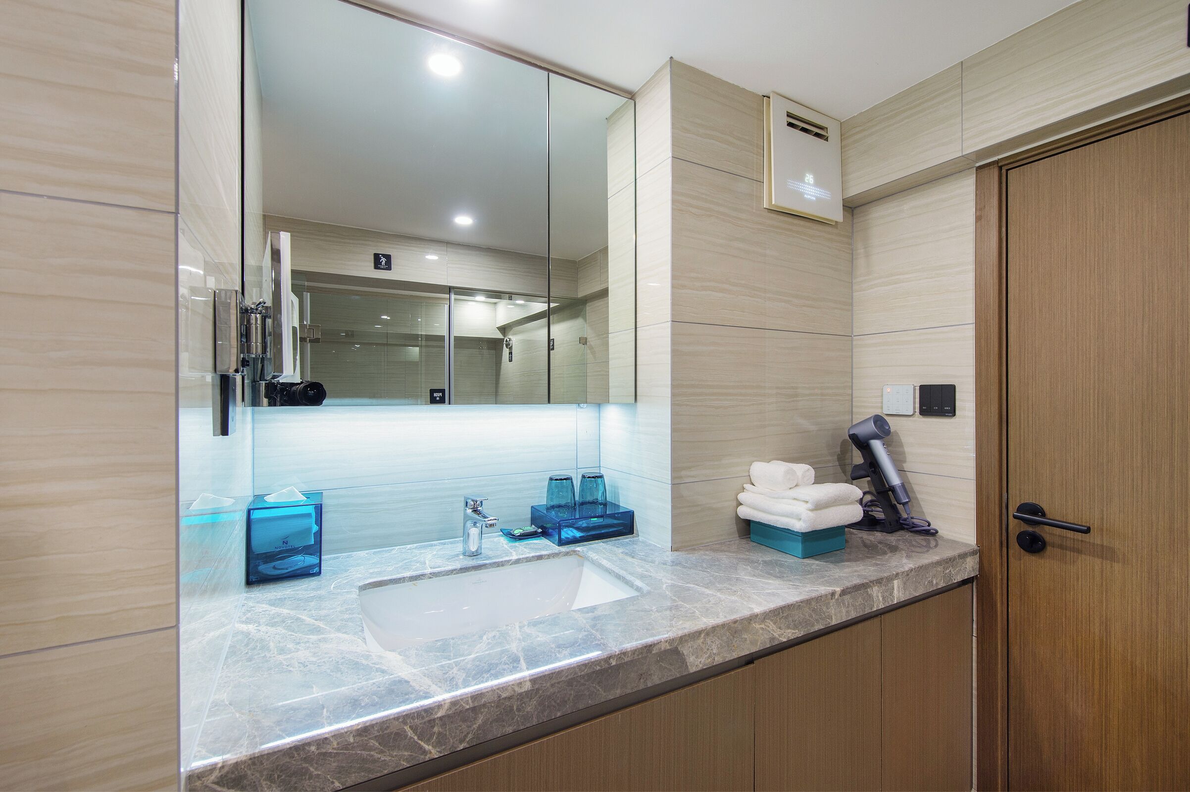 Une salle de bain moderne avec un grand miroir, un lavabo et un porte-serviettes.