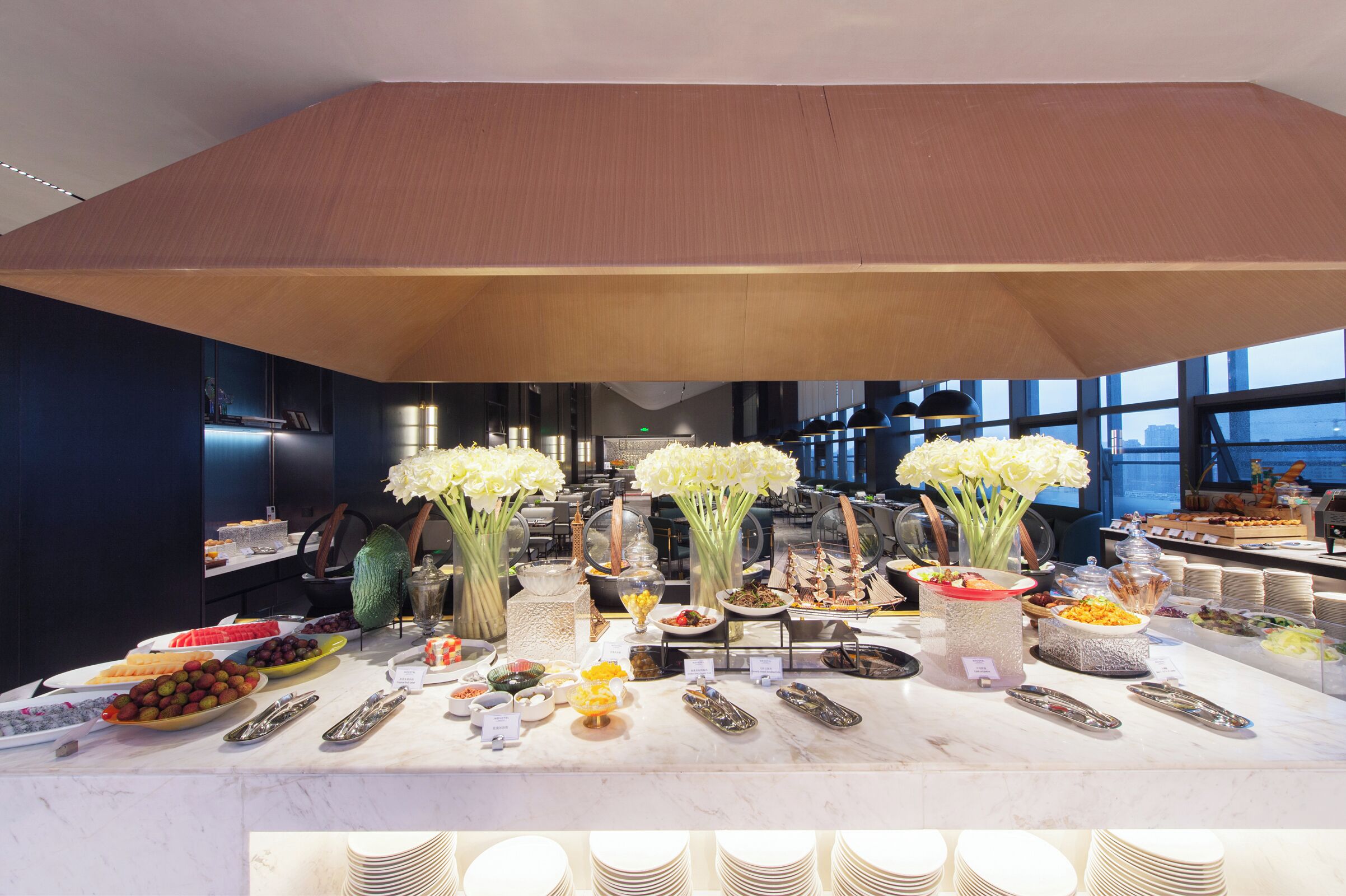 A buffet setup with various food items and a large wooden ceiling structure.