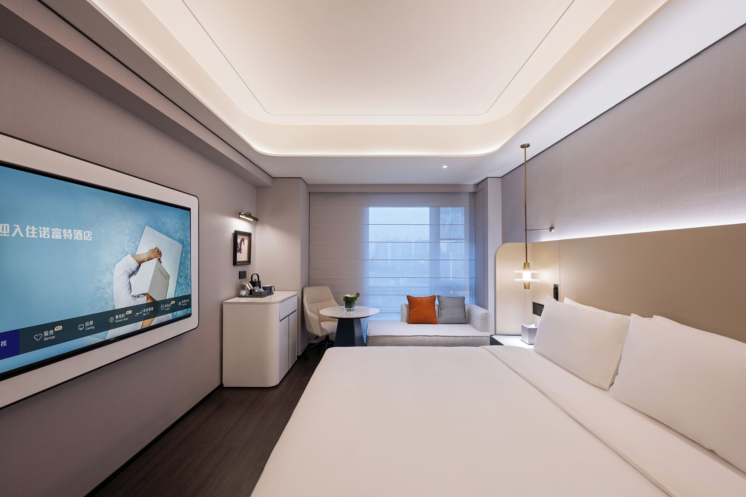 Quarto de hotel moderno com uma televisão de tela plana grande, um sofá, uma cama e uma pequena mesa com um vaso.