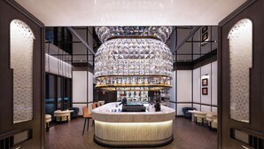 Un lobby lujoso con un bar central, zonas de estar y una imponente lámpara de araña.
