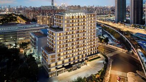 Un hotel Novotel con un diseño moderno, rodeado por un paisaje urbano al anochecer.