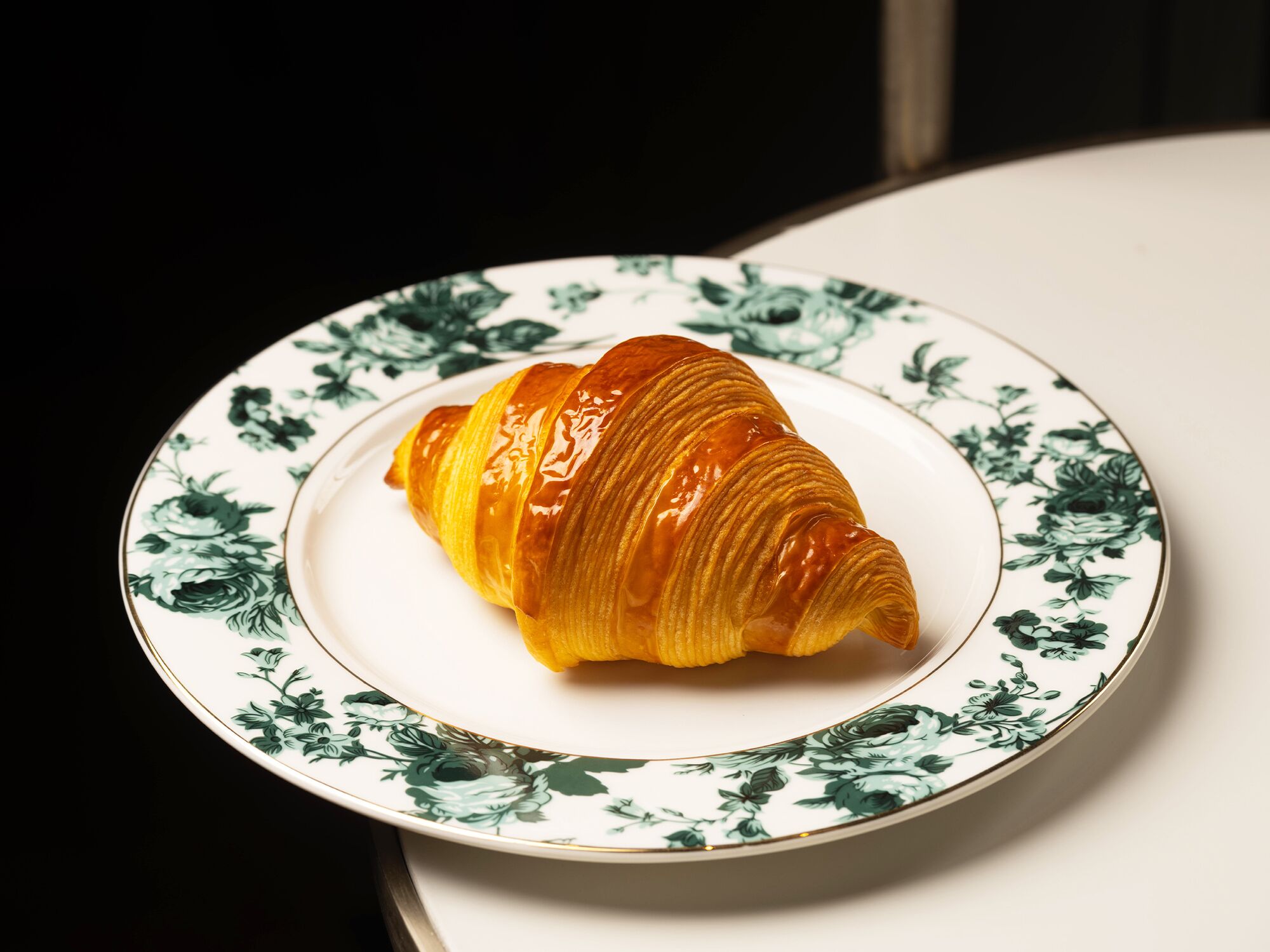 Un croissant sobre un plato con un estampado floral.
