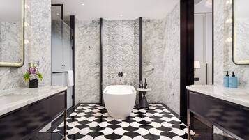 Ein modernes Badezimmer mit einer freistehenden Badewanne, Marmorwänden und einem schwarz-weißen, gemusterten Boden.