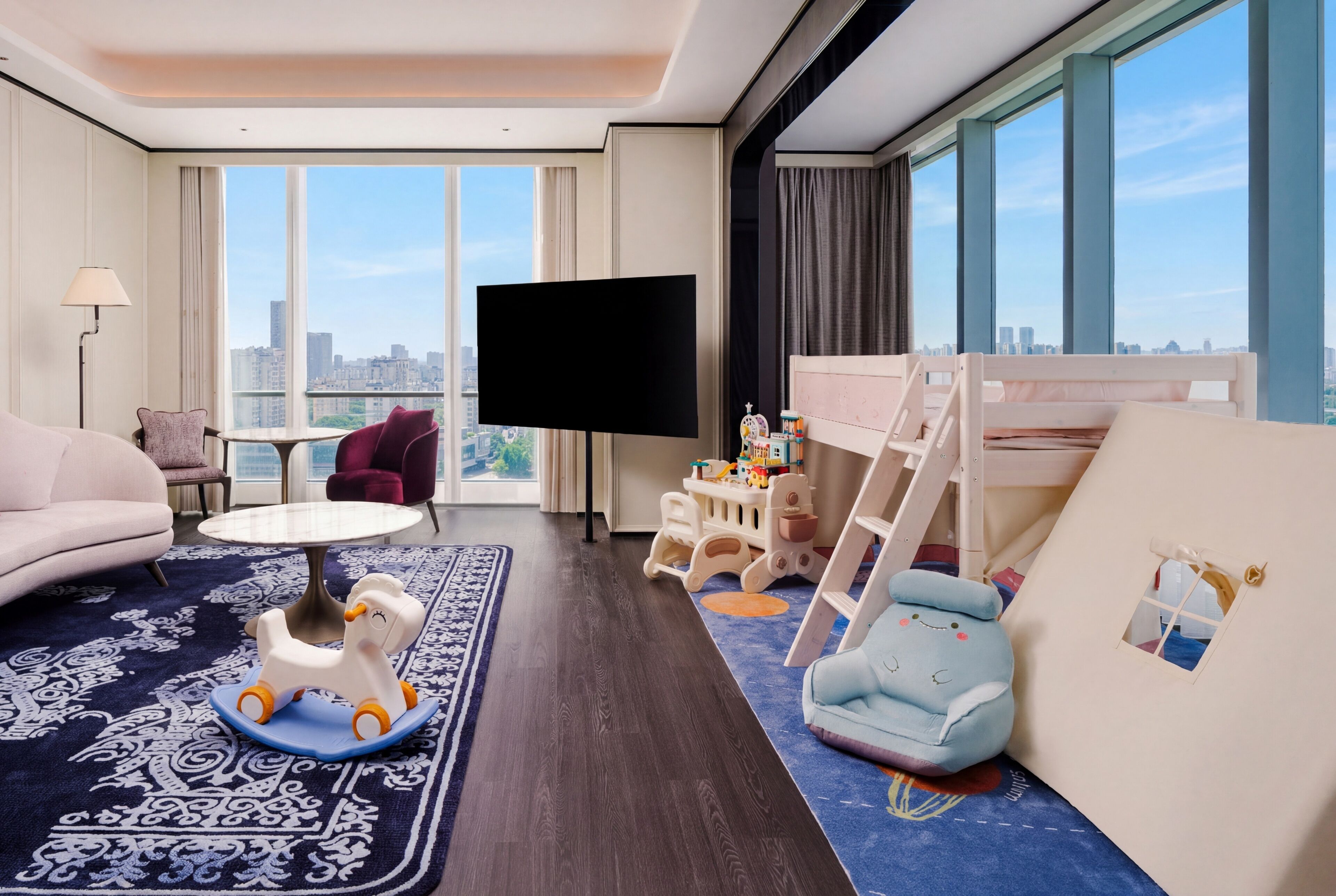 Quarto de hotel com vista para a cidade, TV de tela plana, beliche, mesa pequena e sofá.