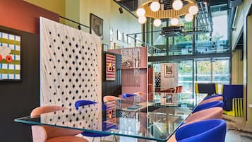 Un interior moderno con una mesa de vidrio, sillas coloridas y obras de arte en las paredes.
