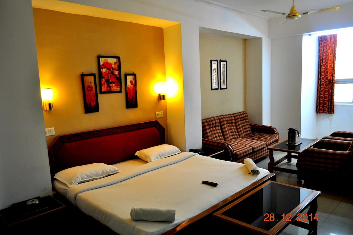Une chambre d’hôtel équipée d’un lit, d’un canapé, d’une table basse et de lampes fixées au mur.