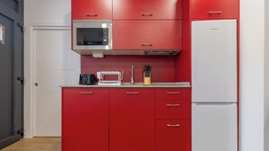 Una cocina con armarios rojos, un microondas, un tostador y un refrigerador.