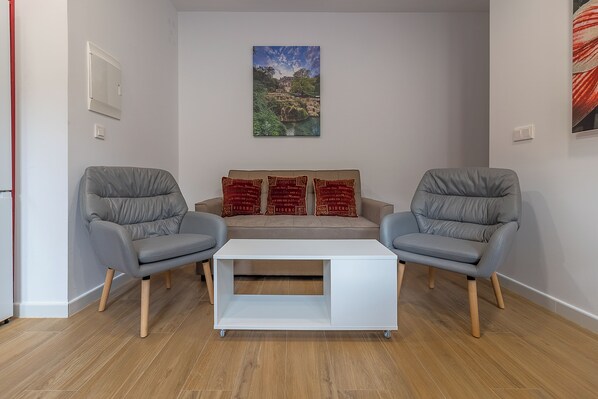 A modern living room with a sofa set, a white coffee table, and two grey armchairs. - Ares III 15 min Teatro Romano, Cuna y Pet Friendly (Merida)