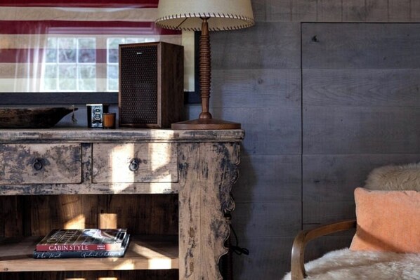 Ein rustikaler Holztisch mit einem Vintage-Radio, einer Lampe und einem Buch mit dem Titel „CABIN STYLE“.