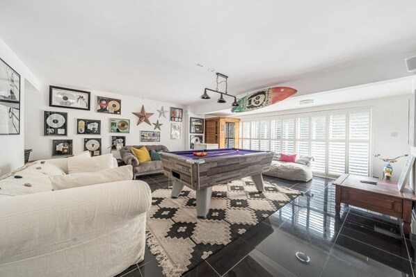 A modern living room with a pool table, a sofa, and a coffee table. - Palm Court Retreats, 2 Luxury Cosy Hideaways on Cornwall’s South Coast (Polperro)