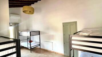 Una habitación con literas, un radiador, una lámpara colgante y una puerta.