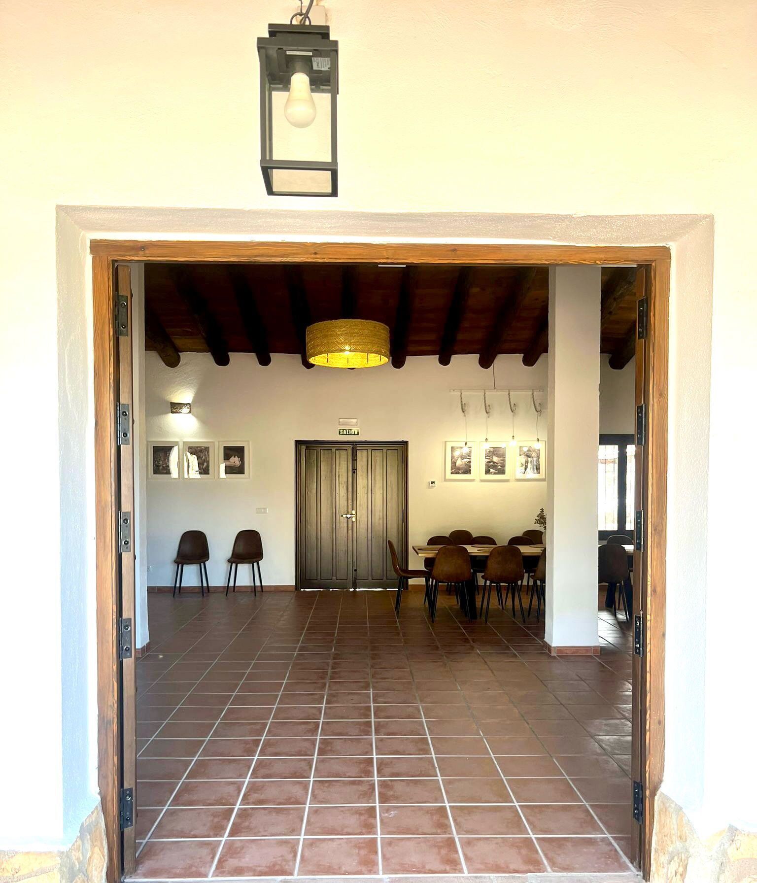 Un comedor con piso de baldosas, techo de madera y una puerta con la leyenda 'SALIDA'.