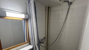 A small bathroom with a shower, a sink, and a mirror.