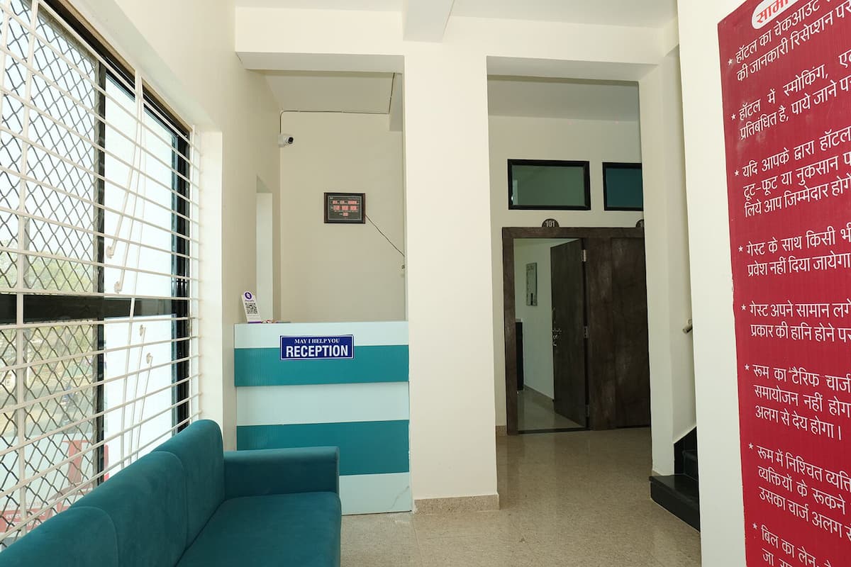 A reception area with a blue and white reception desk, a security camera, and a corridor leading to a door.