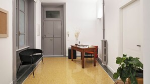 A hallway with a wooden table, a black chair, a potted plant, and a grey door. - Guesthouse Delle Navi  - Room 2 (Roma)