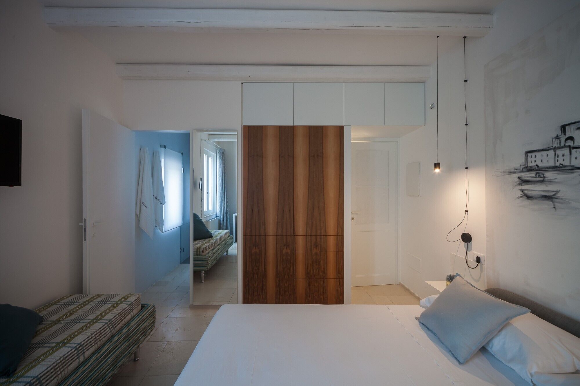 Ein Schlafzimmer mit einem Bett, einem Holzschrank, einem Nachttisch und einer Wandleuchte.