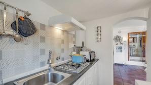 A modern kitchen with a stainless steel sink, a gas stove, and a blue pot on the counter. - Piccola Pigna - Terrazza Vista Mare Sanremo Studio (Sanremo)