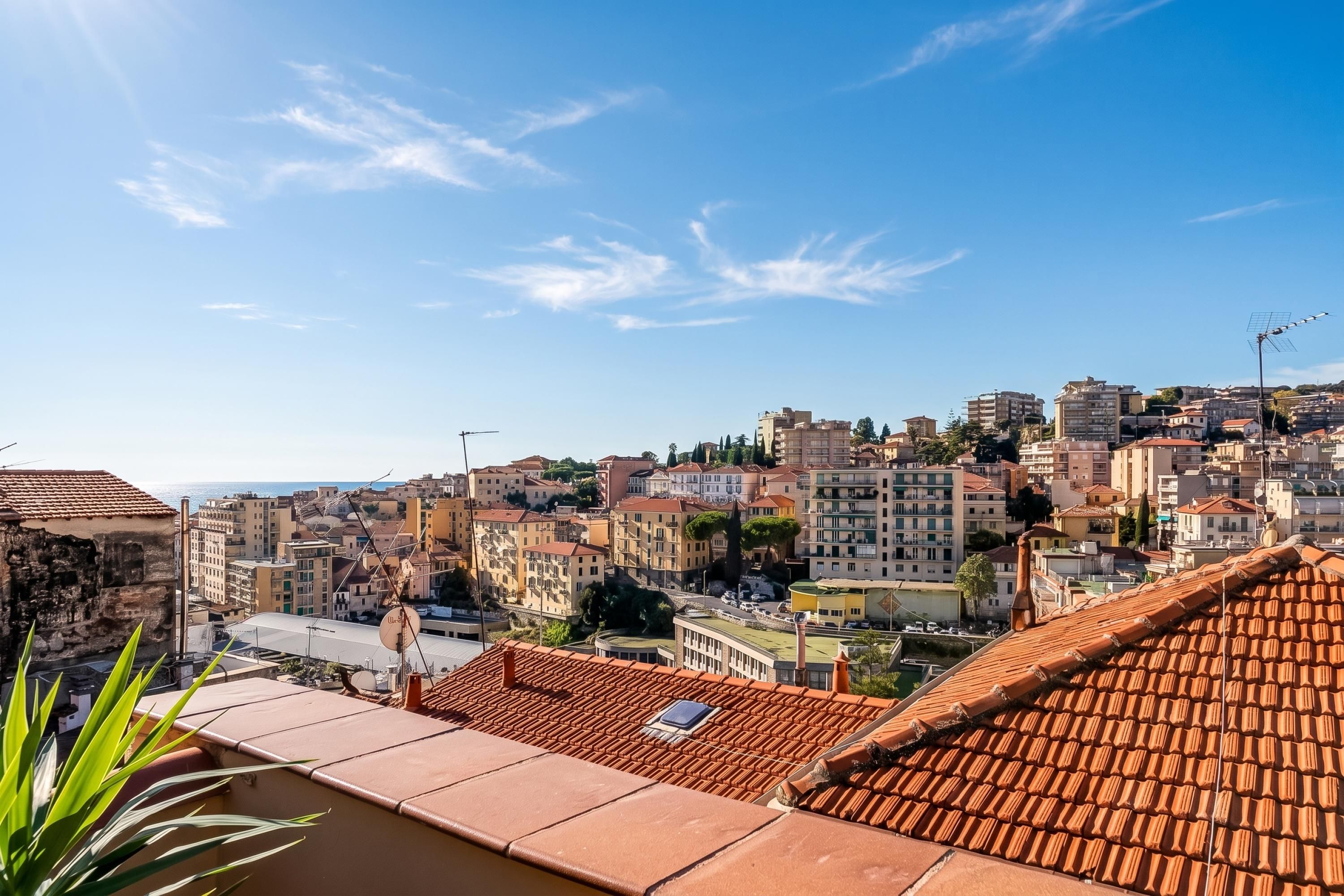 A cityscape with terracotta rooftops and a clear blue sky.