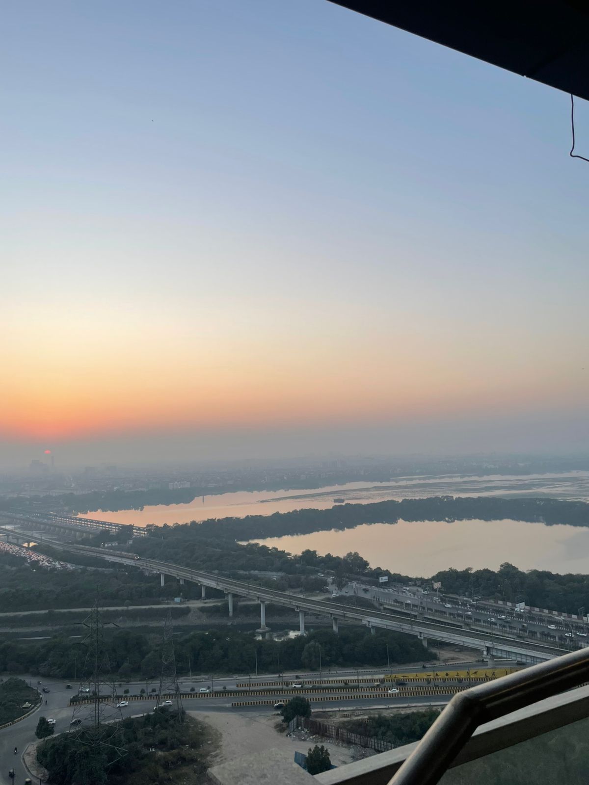 Vista panorámica de un paisaje urbano al atardecer, que incluye un río, varios puentes y una red de autopistas.