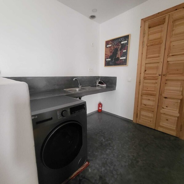 Un espacio de lavandería pequeño con lavadora, lavabo y extintor.