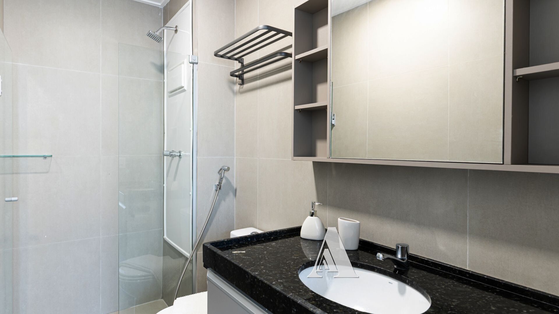 Een moderne badkamer met een douchecabine van glas, een witte wastafel en een zwart aanrecht.
