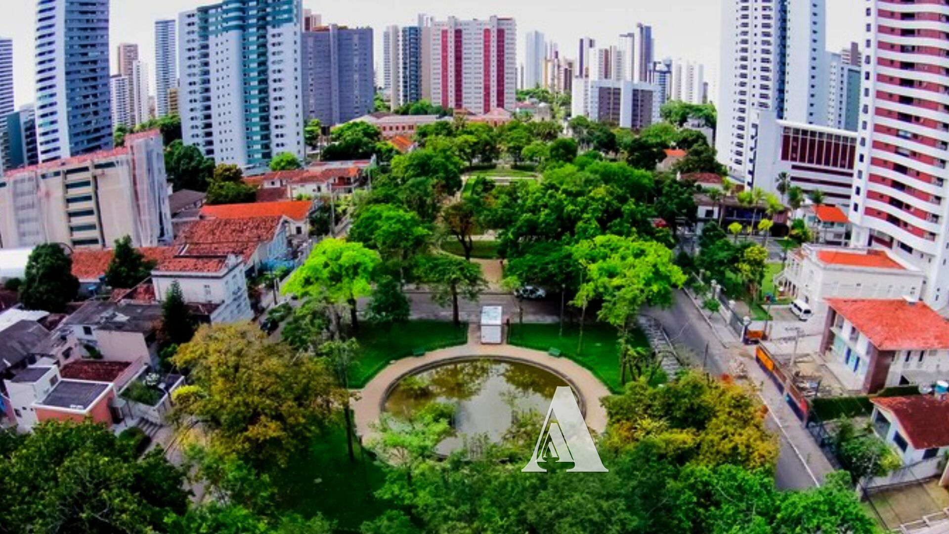 Un quartier urbain dense, caractérisé par de nombreux immeubles de grande hauteur et un parc central agrémenté d’un étang, le tout entouré de bâtiments résidentiels et commerciaux.