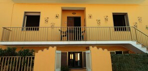 A two-story building with a balcony, a door, and windows. - FOUR-ROOM APARTMENT ON THE 1ST FLOOR (Santa Teresa Gallura)