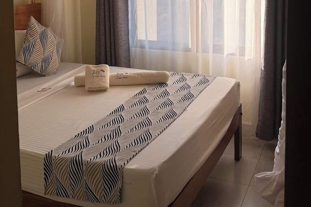 A bedroom with a canopy bed, a patterned bedspread, and a pillow with a leaf design.