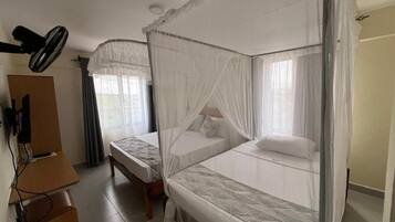 Una habitación con dos camas individuales, un escritorio y un ventilador de techo.