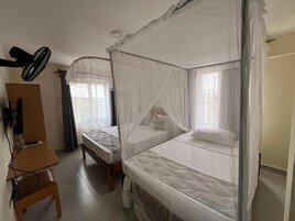 Una habitación con dos camas individuales, un escritorio y un ventilador de techo.