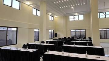 Un salón de conferencias con varias mesas, manteles negros y sillas.