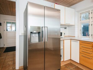 A kitchen with a stainless steel refrigerator, wooden cabinets, a window, and a water dispenser. - 14 Person Holiday Home in Ribe (Ribe)