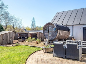 A rustic outdoor seating area with wicker furniture, a barrel-shaped structure, and a brick pathway. - 14 Person Holiday Home in Ribe (Ribe)