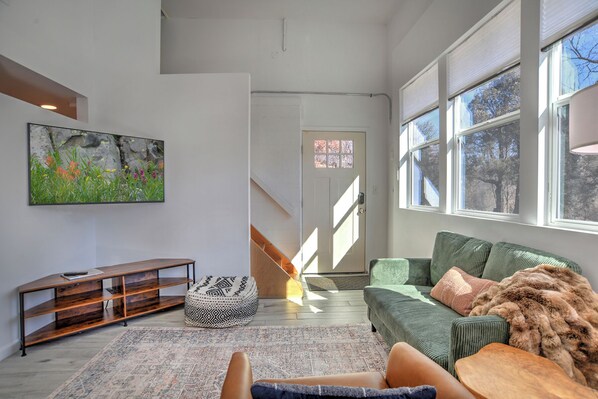 Een moderne woonkamer met een groene bank, een houten salontafel en een kamerkleed met dessin.