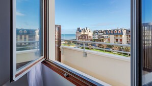 Een balkon met uitzicht op een kustplaatsje, met traditionele architectuur en een heldere lucht.
