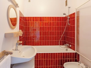 Une salle de bain avec un lavabo blanc, un miroir et une douche.