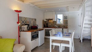 Una cocina compacta con comedor, una lámpara roja, una pequeña isla con electrodomésticos y un salpicadero de azulejos.