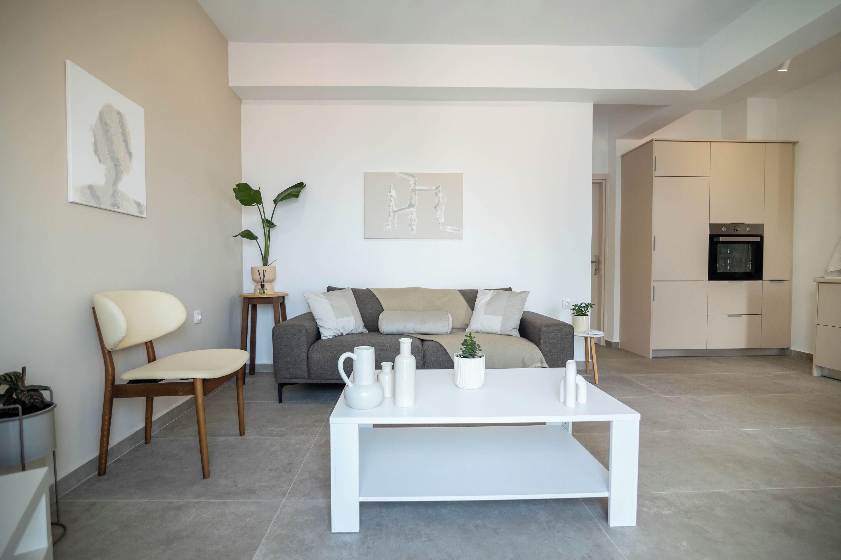 A modern living room with a sofa, a coffee table, and a dining table. There is a kitchen area visible in the background.