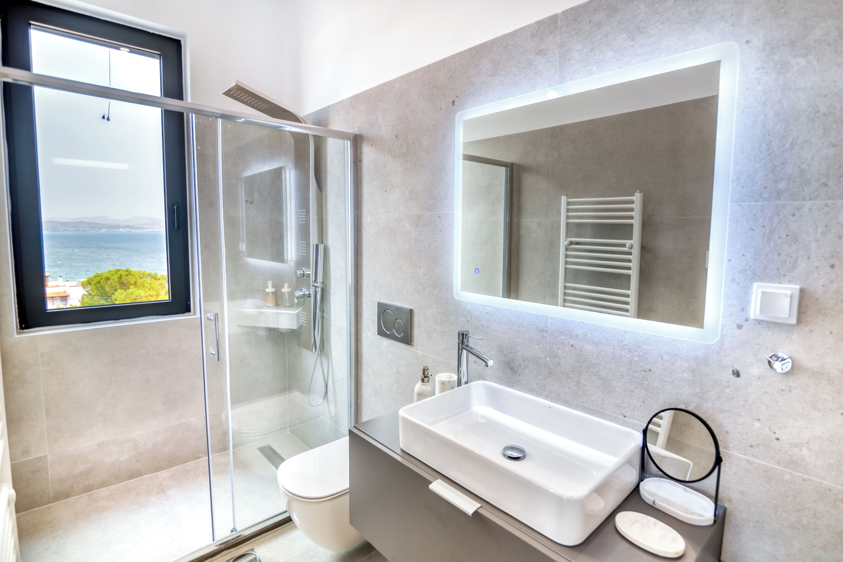 A modern bathroom with a glass shower enclosure, a large sink, and a mirror.