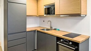 A compact kitchen with a built-in microwave, a sink, and a stove. - Marmotta by Interhome (Leukerbad)