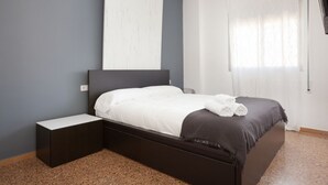 A bedroom with a bed, a bedside table, a large mirror, and a window with curtains. - Duplex with Terrace / Born, Arc de Triomf (08013 Barcelona)